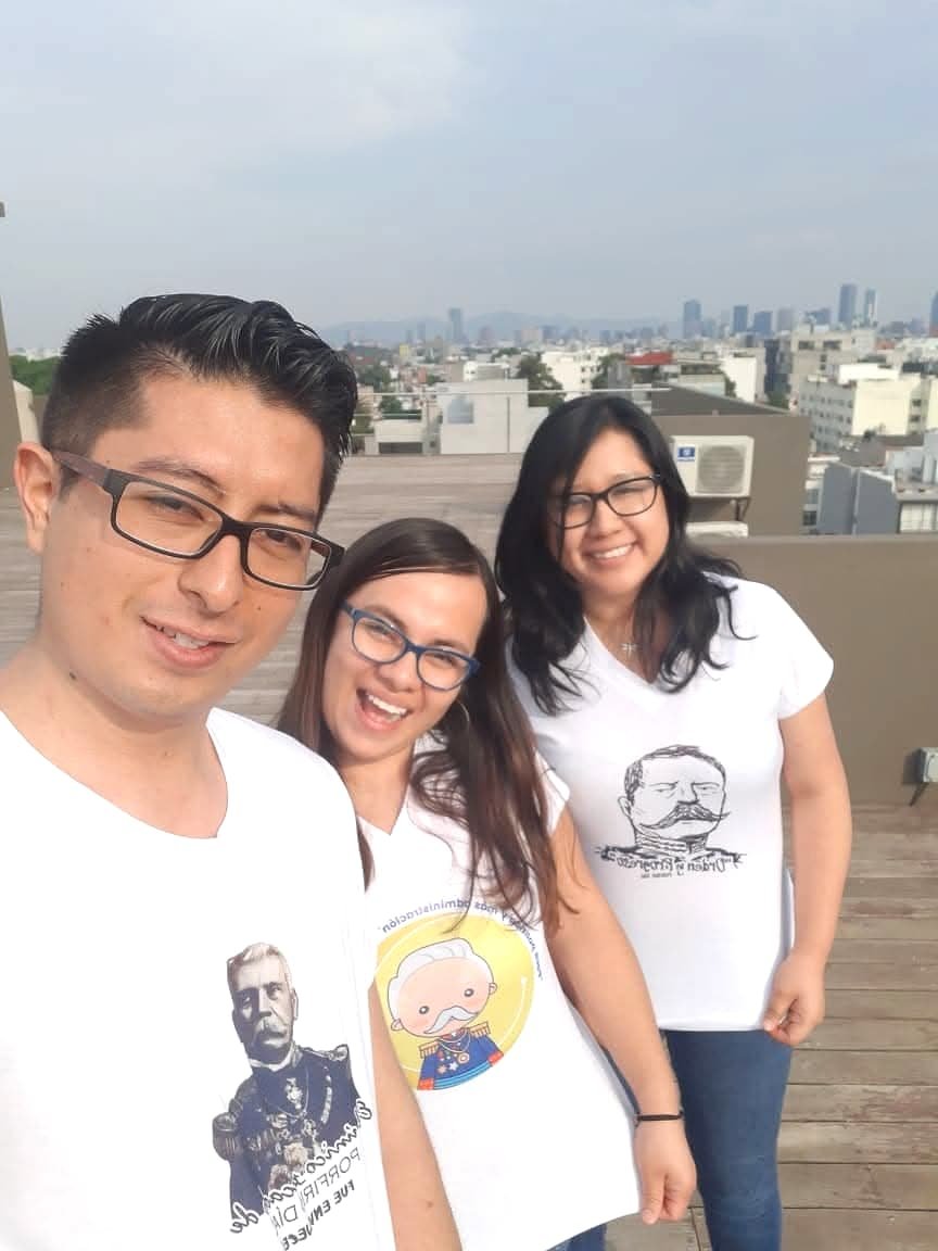 Three team members on a rooftop with Mexico City behind them.