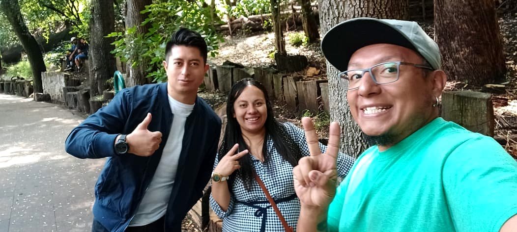 Three team members out in a park, waving at the camera.