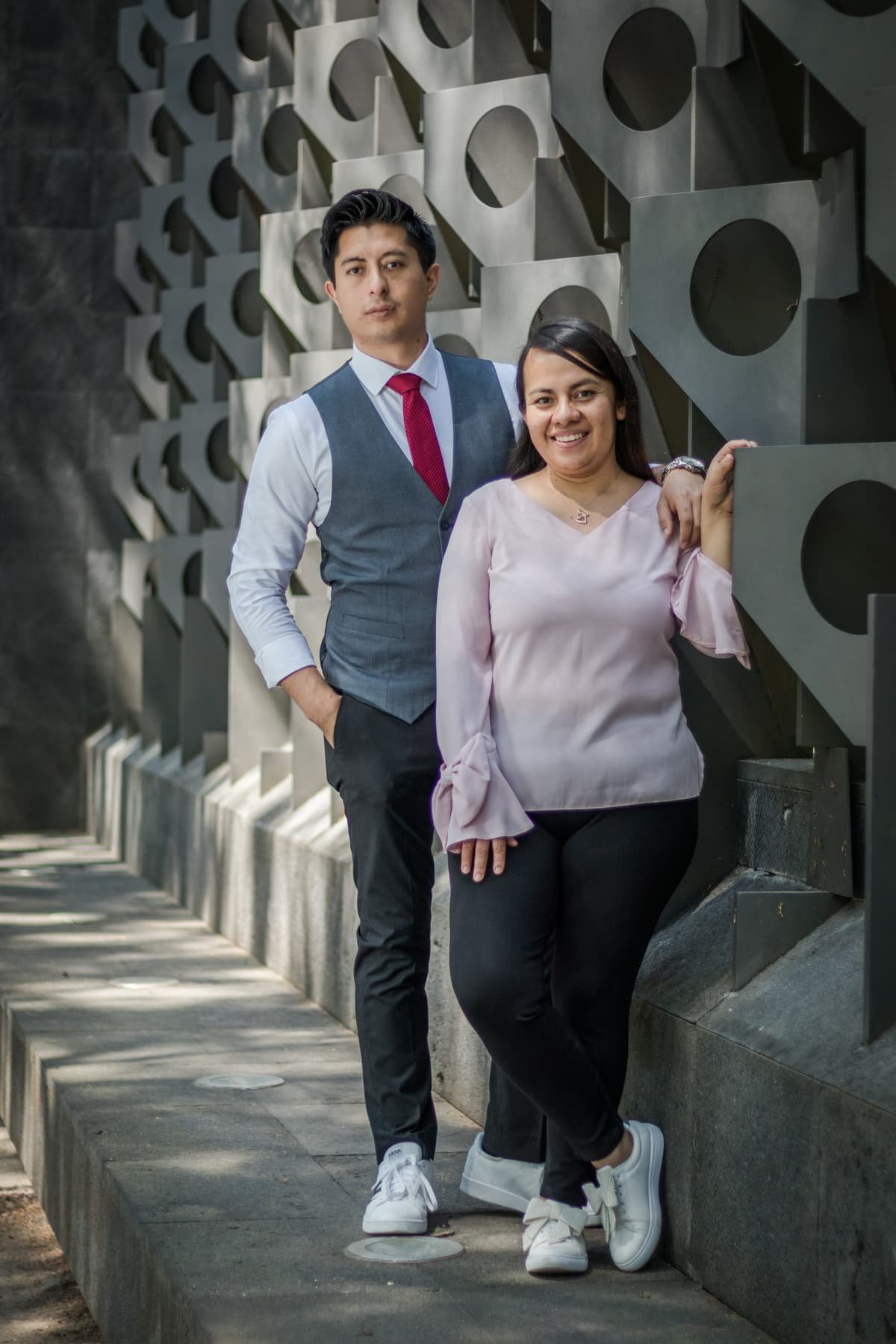 Eduardo and Tania, founders of Editando Ideas, standing in front of a sculptural concrete wall.